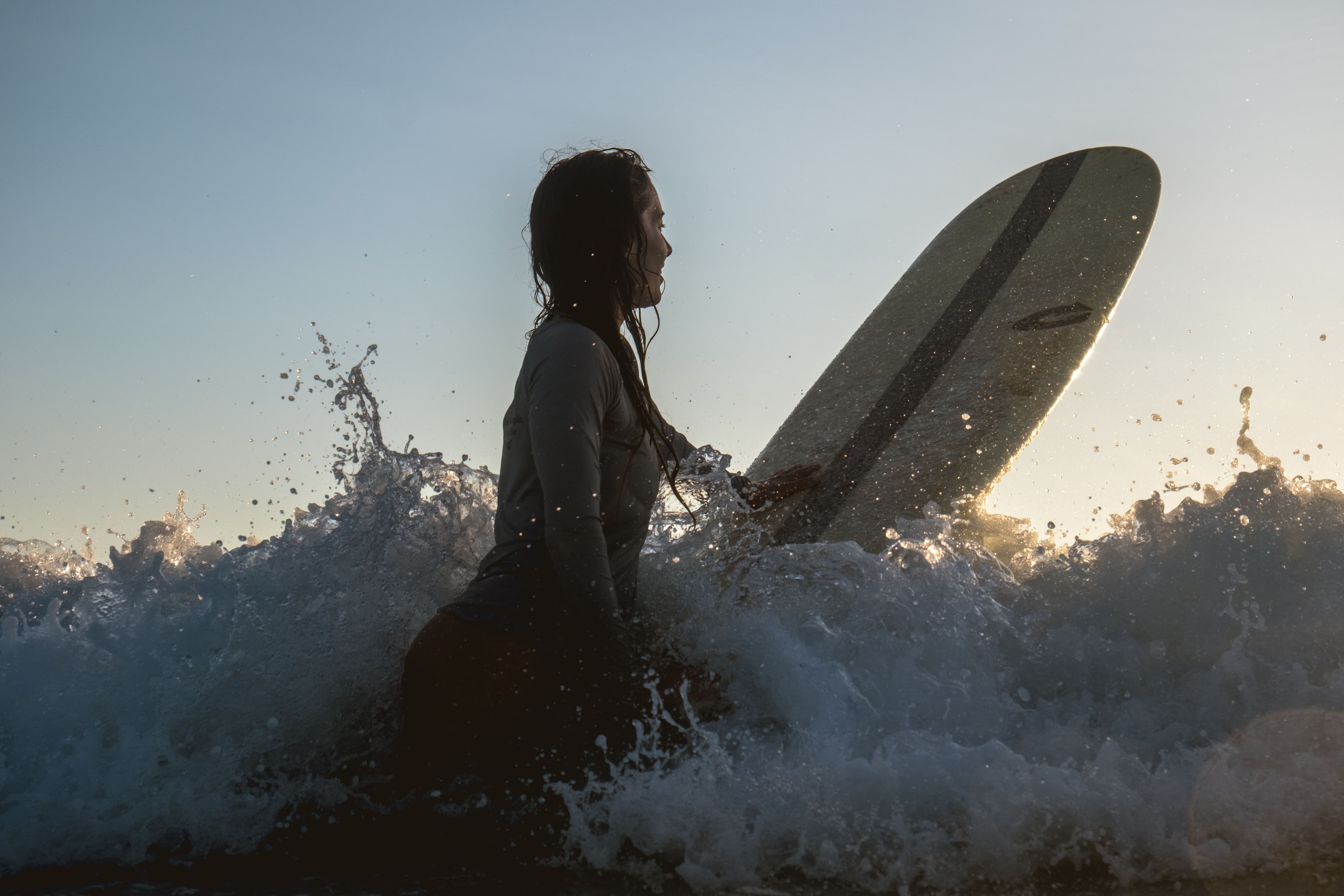 Rachelle Robinett on a surfboard with whitewater waves around her